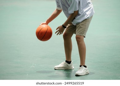 Dribbling Basketball on Outdoor Court in Shorts and Sneakers - Powered by Shutterstock