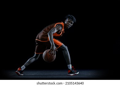 Dribbling. Portrait of young african man, basketball player training with ball isolated over black studio background. Concept of professional sport, healthy lifestyle, motion and action - Powered by Shutterstock