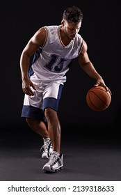 Dribbling Pro. Studio Shot Of A Basketball Player Against A Black Background.