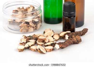 Dried Acorus calamus roots, also known as sweet flag, and bottles with oil and extract isolated on light background. For personal care products, beauty and medicine. Close up.