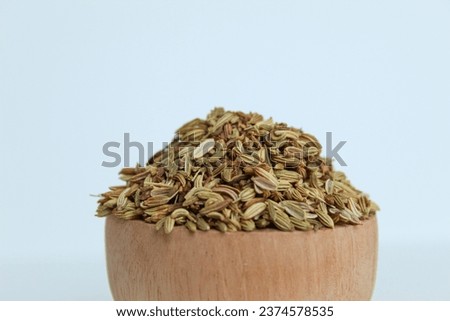 Dried Aniseed, or Pimpinella Anisum seed, or Adas Manis, inside wooden bowl. Isolated on black background