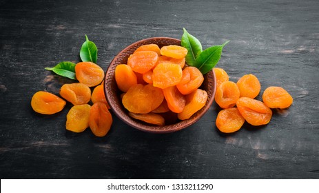 Dried apricots in a bowl on a black background. Top view. Free space for your text.