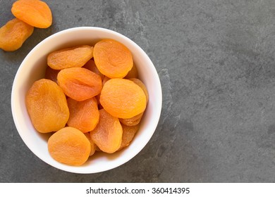 Dried Apricots, A Healthy Snack Containing Vitamins, Beta-carotene, Fiber, Antioxidants, Photographed Overhead On Slate With Natural Light (Selective Focus, Focus On The Apricots On The Top)