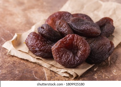 Dried apricots on craft paper, brown background, healthy concept.