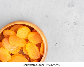 Dried apricots in a wooden bowl on gray concrete background. Healthy eating concept. Top view
