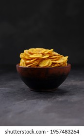 Dried banana chips or banana waffers,arranged beautifully in a clayor earthenware with grey textured background, isolated.