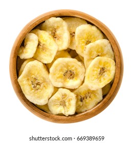 Dried Banana Chips In Wooden Bowl. Yellow Deep Fried Slices Of Bananas, Covered With Sugar Or Honey. Snack With Sweet Taste. Isolated Macro Food Photo Close Up From Above On White Background.