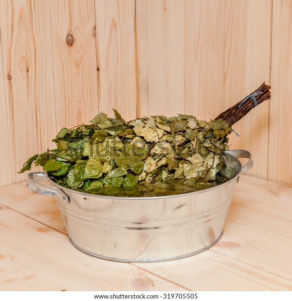 Dried birch branches of\
besom (banny venik) moistened with very hot water before use in\
traditional Russian banya (sauna or bathtub). Wooden background in\
banya interior.