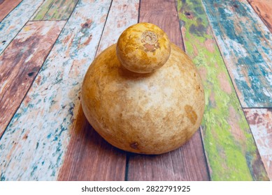 Dried Bottle Gourd with Rustic Tan Texture Resting on Colorfully Weathered Wooden Planks