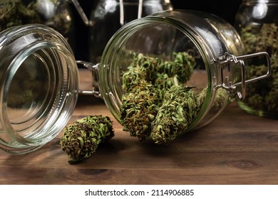 Dried Cannabis Hemp Buds Spill Out Of A Glass Jar, Ready For Consumption.