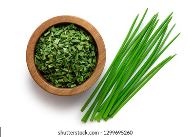 Dried chopped chives in a dark wood bowl next to a pile of whole fresh chives isolated on white from above. - Powered by Shutterstock