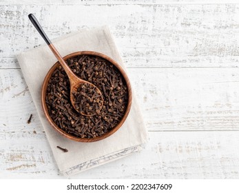 Dried cloves in wooden bowl on white wooden table. Condiment, spice, flavouring and cooking ingredient. Top view food. Copy space. Wooden spoon, kitchen textile napkin. - Shutterstock ID 2202347609