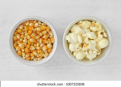 Dried corn kernels and pop corn in bowls on wooden background