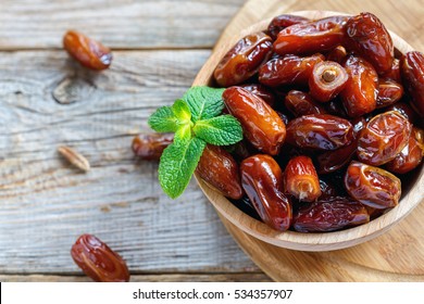 Dried date and green mint in a bowl on old wooden table close up. - Shutterstock ID 534357907