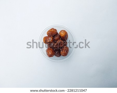 Dried dates fruit or kurma on plastic cup, isolated white background
