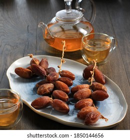 Dried Dates Fruit On Oval Plate Above Brown Wooden Table, Serve With Tea On Brown Table Background 