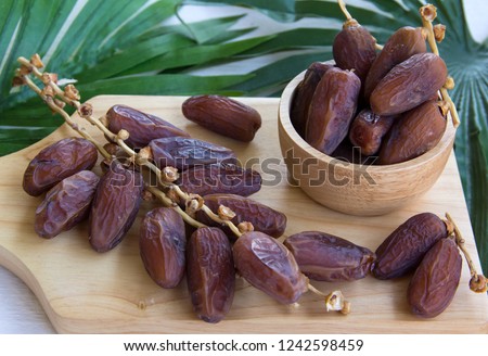 dried dates fruit on wooden table with palm leaves, high energy fruit full of nutrition, good for breastfeeding mom 