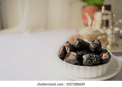 Dried dates fruits, also known as kurma ajwa, typical fruits during Ramadhan. Very healthy food. served in white plate and white background.