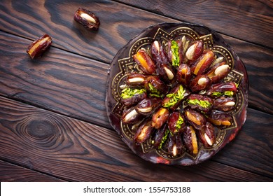 Dried dates stuffed with candied fruits and nuts on a rustic wooden table. Top view flat lay background with copy space.