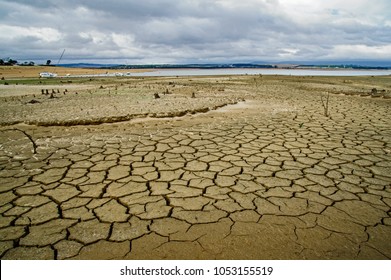 dried up earth of an empty water reservoir with dark clouds giving the promise of rain during the water crises and drought of the Western Cape Province of South Africa