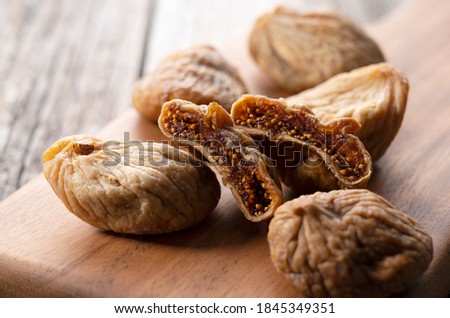 Dried figs on a cutting board set against an old wooden backdrop