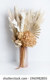 Dried flower arrangement in a pink vase. Including Banksia, Hydrangea, pampas grass, Palm Fronds, cream Ruscus leaves, and rust Amaranthus. Photographed on a white background. - Shutterstock ID 1965982855