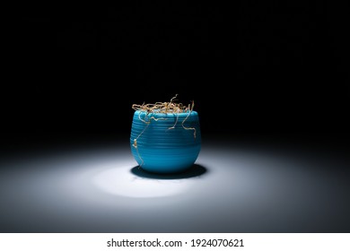 A Dried Flower In A Turquoise Pot In The Dark Sanctifies A White, Bright Light. A Dead Flower In A Vase On A Black Background, White Light. A Wilted Houseplant. Dry Plant.