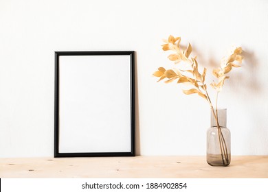 Dried Flowers And A Photoframe Against A Light Wall In A Minimalist Style