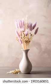 Dried flowers in vase on table against light grey background