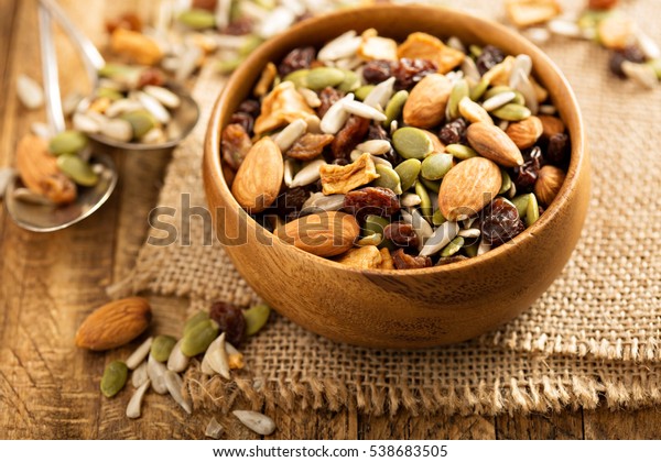 Dried fruit and nuts trail mix with
almonds, raisins, seeds and apples in a wooden
bowl