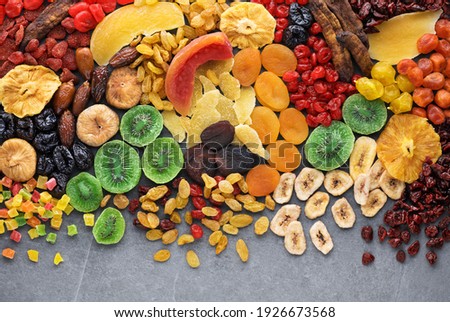 Dried fruits and berries on gray background top view. Lemons, oranges, bananas, raisins, cranberries, kiwi, cherries, ginger, plums, strawberries, dried apricots, tangerines, dates, pineapples, figs,