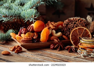Dried fruits and nuts on an old wooden table. Christmas still-life with dried citrus, apricots, raisins, various nuts, cinnamon sticks, and anise. - Shutterstock ID 2229023323