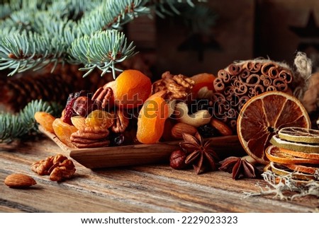 Dried fruits and nuts on an old wooden table. Christmas still-life with dried citrus, apricots, raisins, various nuts, cinnamon sticks, and anise.