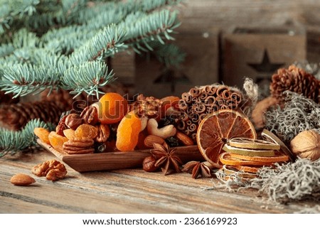 Dried fruits and nuts on an old wooden table. Christmas still-life with dried citrus, apricots, raisins, various nuts, cinnamon sticks, and anise.