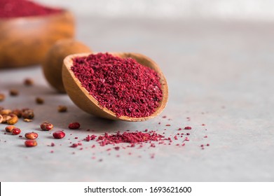 Dried Ground Red Sumac Powder Spices In Wooden Spoon With Sumac Berries On Rustic Table. Healthy Food Concept