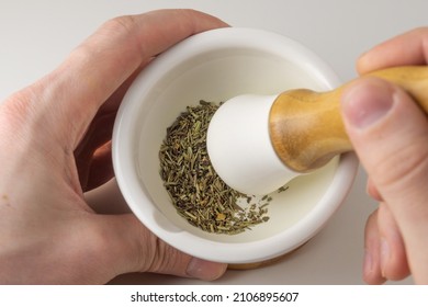 Dried herbs are crushed in a mortar and pestle. Men's hands grind spices with a mortar. Cooking spices from french herbs, oregano, rosemary. - Powered by Shutterstock