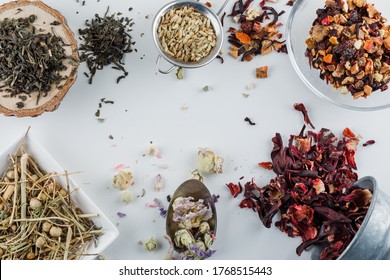 Dried Herbs In Spoon, Sieve, Plates, Bucket With Wooden Board Flat Lay On A White Background