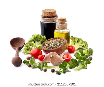 Dried herbs in wooden bowl, olive oil, balsamic vinegar  on the white background with fresh  vegetables. Spices with tomatoes, broccoli and garlic.