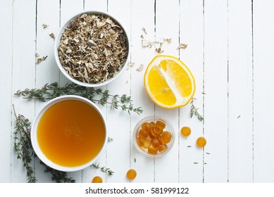 Dried Iceland Lichen Leaves, Honey, Lemon, Thyme Twigs, Pills On White Wood Table Background