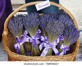 Dried lavender flower bouquets with purple ribbon in a wicker basket at the market