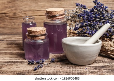 Dried lavender flowers in a in a mortar and pestle with bottle of essential lavender oil or infused water. Old books and lavender flowers bunch in the wooden background, close up