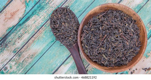 Dried Loose Black Darjeeling Tea Leaves In Wooden Spoon And Bowl Over Wooden Background