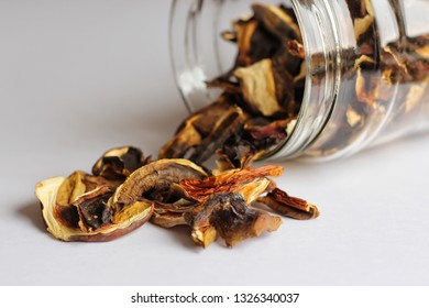 Dried mushrooms is pouring from a glass jar. Light background, horizontal orientation, copy space
