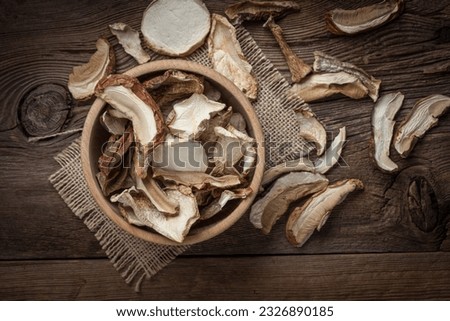 Dried mushrooms in wooden bowl on dark background. Top view.