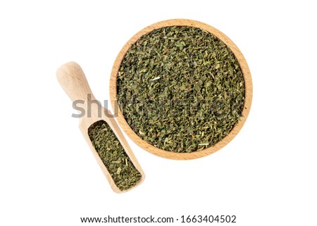 dried nettle herb or in latin Utricae folium in wooden bowl and scoop isolated on white background. medicinal healing herbs. herbal medicine. alternative medicine