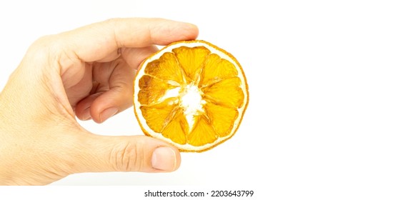 Dried Orange Slice Isolated On White Background. Hand Holding A Slice Of Citrus Fruit. Selective Focus.