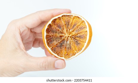 Dried Orange Slice Isolated On White Background. Hand Holding A Slice Of Citrus Fruit. Selective Focus.