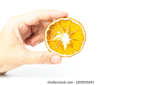 Dried Orange Slice Isolated On White Background. Hand Holding A Slice Of Citrus Fruit. Selective Focus.