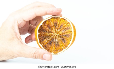 Dried Orange Slice Isolated On White Background. Hand Holding A Slice Of Citrus Fruit. Selective Focus.