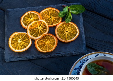 Dried Orange Slices. On Black Slate Board With Natural Edge. Decoration - Sprig Of Fresh Peppermint. Tea With Dried Orange Slices And Mint Leaves. Mentha Balsamea Wild